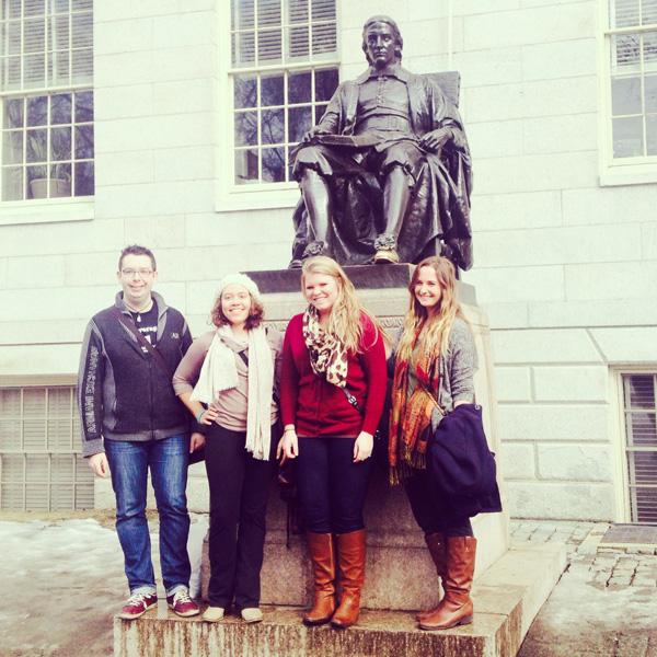 (Left to right)  Hamline students Kevin Watson, Mia Jackman, Maggie Blackmon and Sofia White from the Values in Action program pose in front of the John Harvard statue on campus.