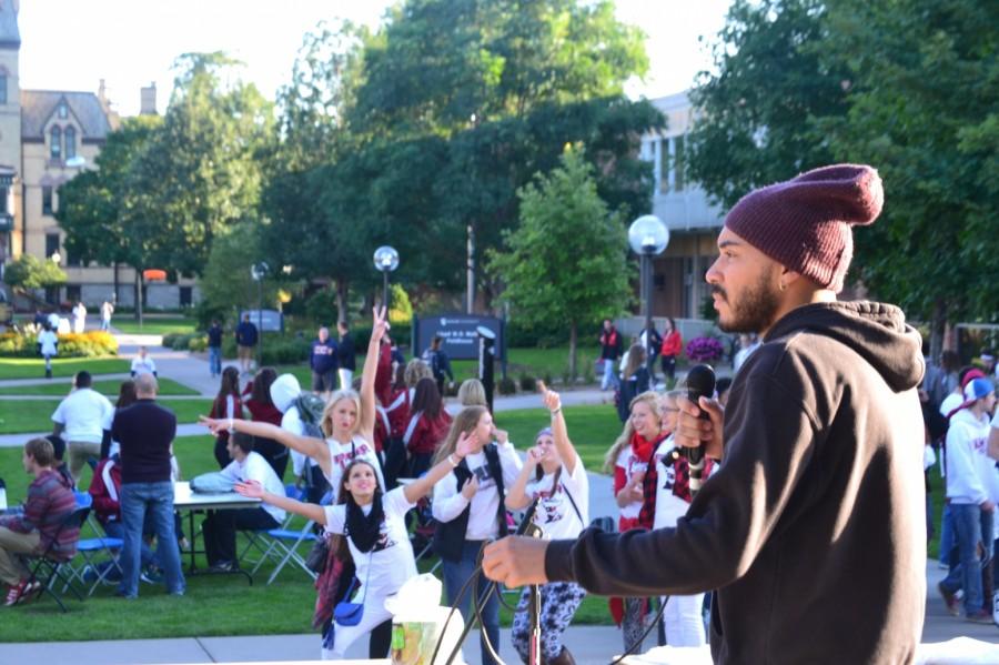 HU Alum Ellis Richardson, stage name Ellis Cleve, performs in front of Klas Center. In the background, Hamline volleyball seniors (left to right) Lynsey Reimer, Stephanie Kaup and Paige Walters strike a pose.