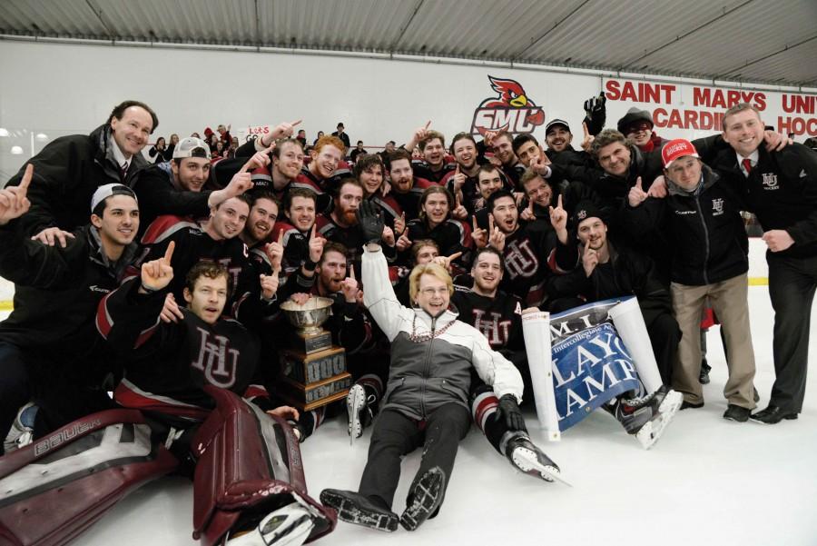 The Hamline Pipers mens ice hockey pose for a photo op with President Linda Hanson after winning their second ever conference championship.