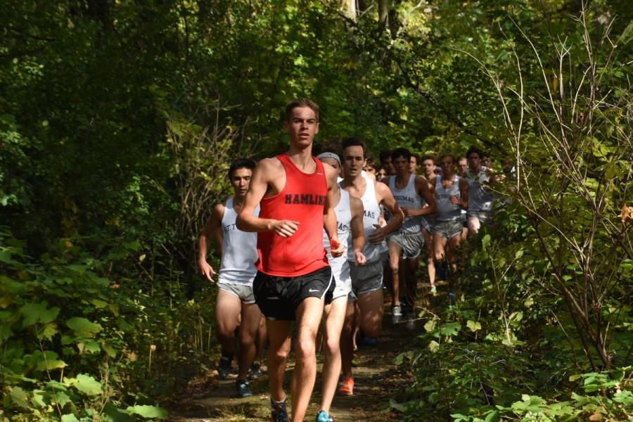Through the forest, James Logan leads a pack of cross country runners during the first lap of the Saint Kate’s meet on October 10.