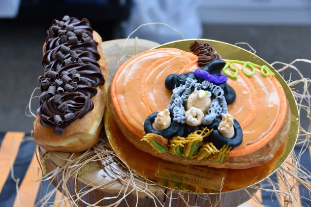 The decorated Witches Brew Donut from Dorothy Anns Bakery & Cafe a pumpkin-shaped raised donut filled with a pumpkin cheesecake stuffing and Grandma Gs ginger snap cookie crumble and a pumpkin pie spiced icing on top. 