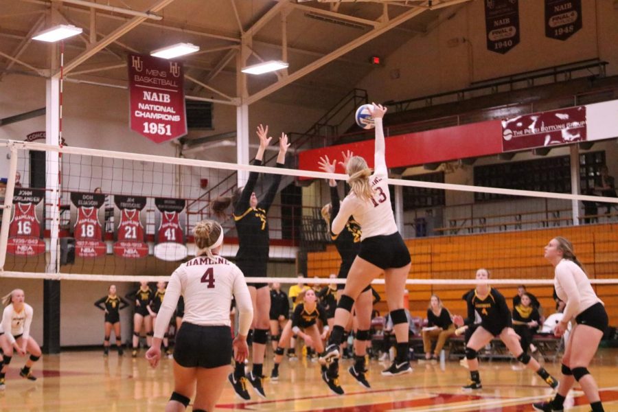 Junior Madison Hurrle tries to hit the ball past two Gustavus Adolphus blockers during a game on Oct. 5.