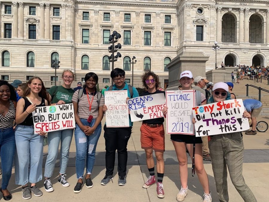 From left, first-years Pearl Buabeng, Raina Meyer, Sarah Kennedy-Croft, Fatima Raye Menawa, Anthony Meng, William Nelson, Hope Nordrum and Eliza Hagstrom hold signs at the climate strike on Sept. 20 in front of the state capital.