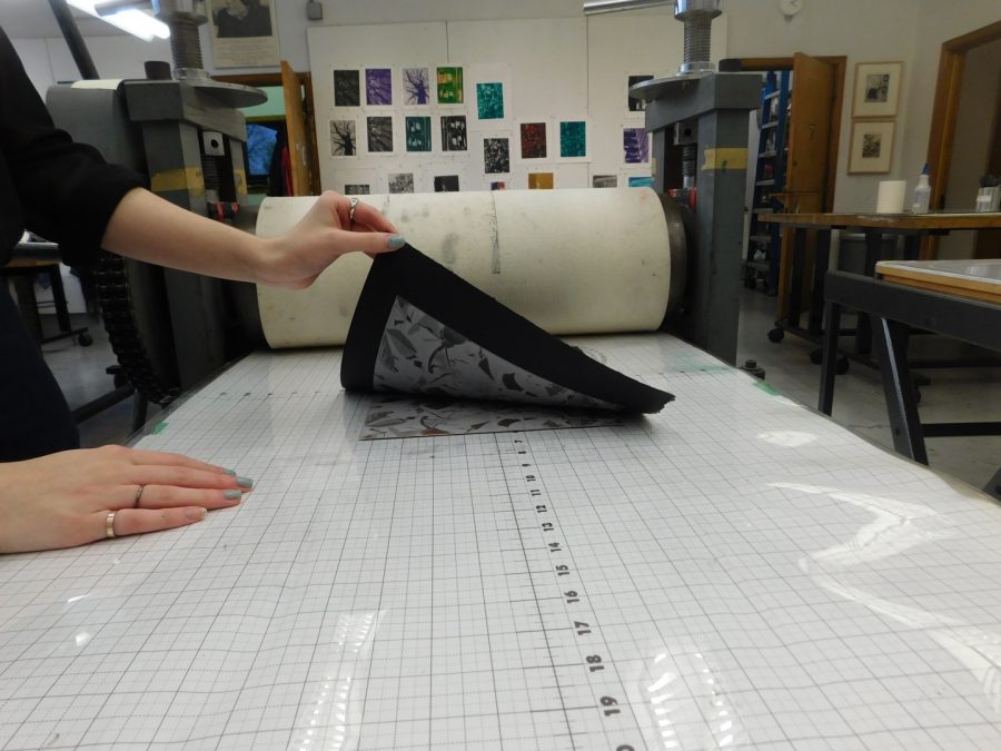 The black paper is lifted up slowly to reveal the printed design. The original design plate remains on the surface. This can be repeated multiple times for color variations. 