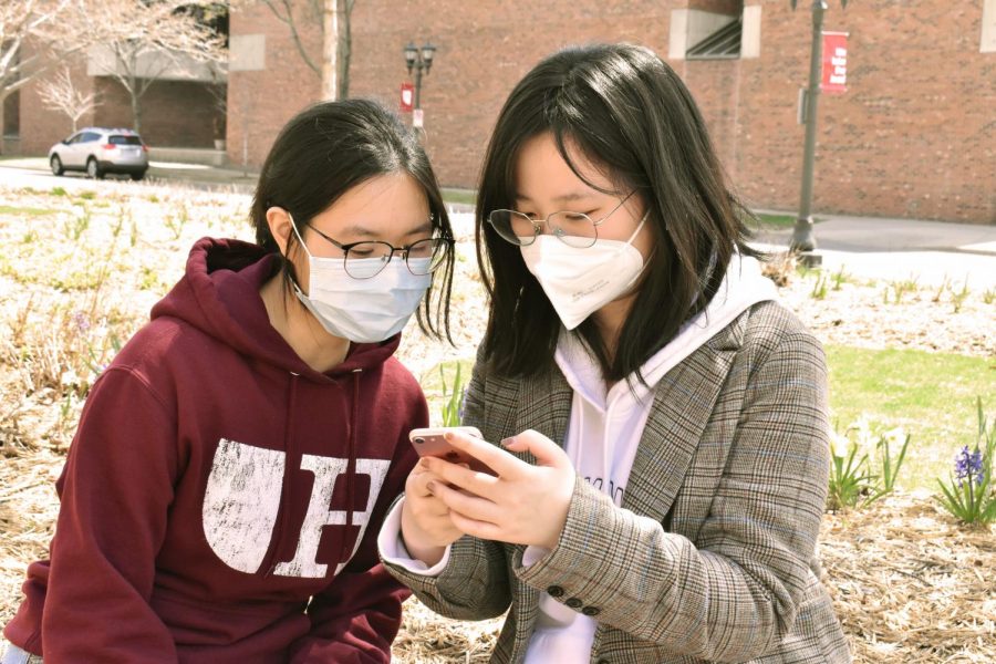 Juniors Ziqiao Ma and Zhaoying Chen share a moment in the sun outside of Drew Residence Hall, both wearing face masks. 