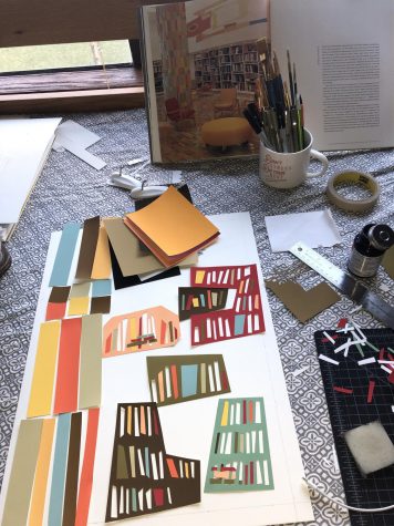 A vertical photograph showing a partly-completed piece of artwork. Colored paper cut into strips are placed on a white poster as the artist makes decisions about how to visually construct their artwork. In the background are pictured art materials such as glue, paintbrushes, and cutting tools. Also in the background is a photo of a library or reading room being used as reference for the artwork.
