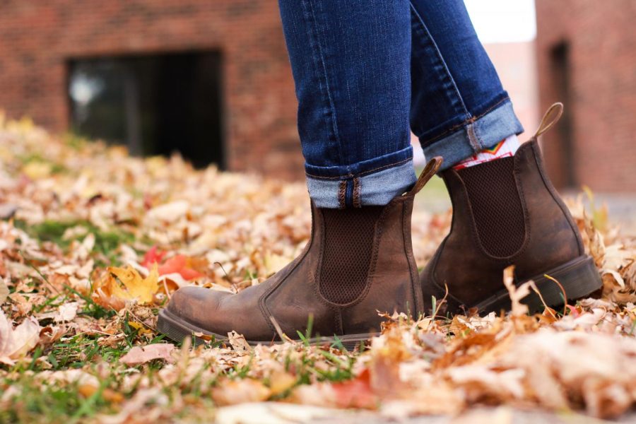 A pair of brown boots against a background of orange and red leaves