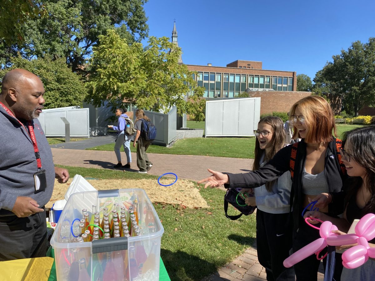 Associate Vice President of Student Affairs Carlos Sneed encourages a group of students in the midst of a ring toss for the grand prize, a bottle of Jarritos.