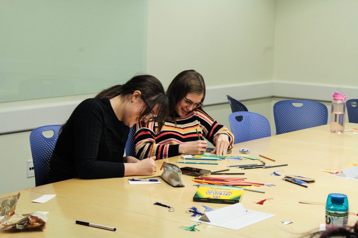 Second-years Melanie Leverich and Bella Stadheim share a laugh as they decorate their bookmarks with colored pencils and an array of colorful tassles.
