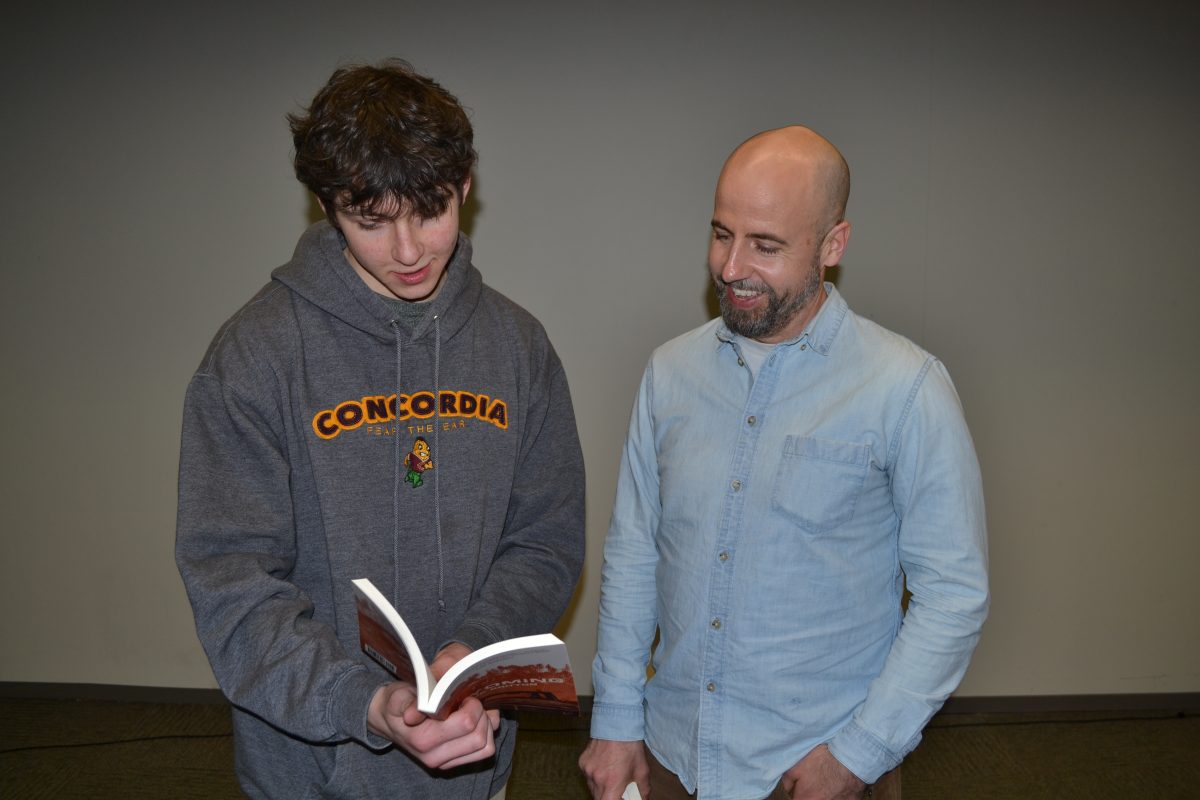 First-year Hennepin College student Valentine Chernyak (left) and JP Gritton (right) share a smile over Gritton’s book, Wyoming.