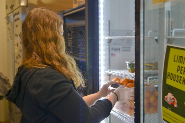 First-year Kaitlynn Fuller stocks one of the FRC fridges with oranges as FRC staff unloads the Friday Trader Joe’s delivery.