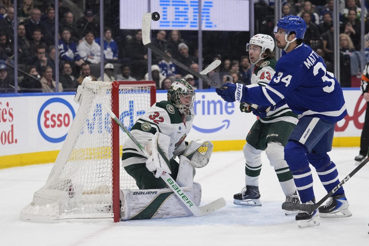 Jan 19, 2026; Toronto, Ontario, CAN; Toronto Maple Leafs forward Auston Matthews (34) plays a puck in the air against Minnesota Wild goaltender Filip Gustavsson (32) and defenseman Quinn Hughes (43) during the first period at Scotiabank Arena. Mandatory Credit: John E. Sokolowski-Imagn Images