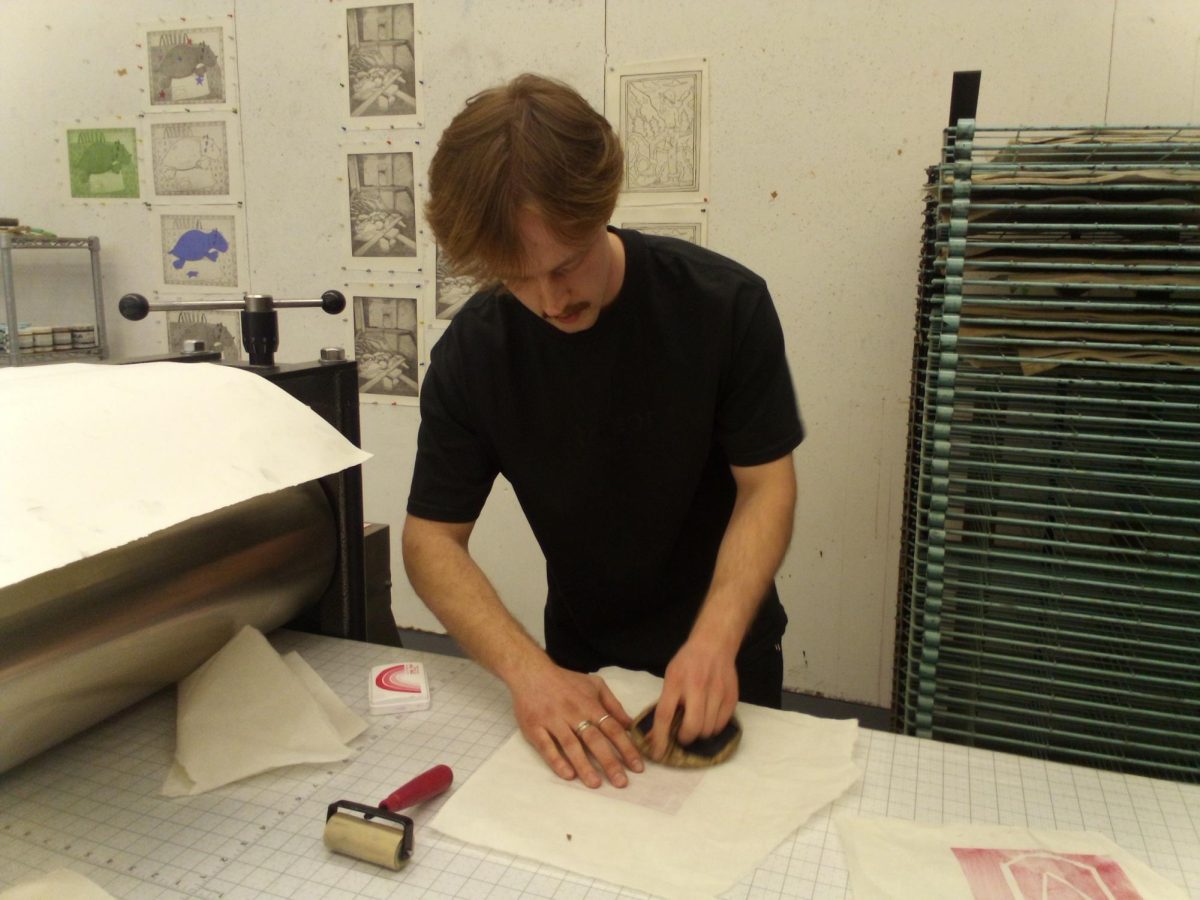 Sculpture Guild President senior Soren Goebel tests out prints made by attendees at the art build ahead of the vigil, which the artists got to keep a copy of to take home. Goebel is printing on kozo paper, a high quality type of Japanese paper.
