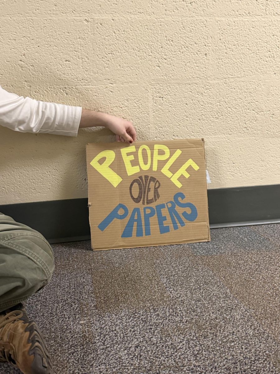 Senior Alex Bailey shows off the homemade People over Papers sign they were asked to remove from their window.